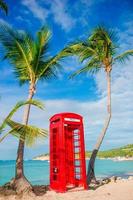 rood telefoon stand in van Dickenson baai antigua. mooi landschap met een klassiek telefoon stand Aan de wit zanderig strand in antigua foto