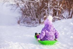 weinig schattig meisje trekt een slee in warm winter dag foto