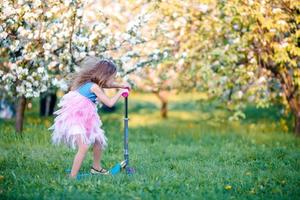 weinig meisje hebben pret in bloeiend appel boom tuin Aan voorjaar dag foto