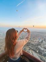 gelukkig vrouw gedurende zonsopkomst aan het kijken heet lucht ballonnen in Cappadocië, kalkoen foto