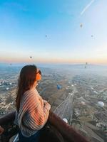 gelukkig vrouw gedurende zonsopkomst aan het kijken heet lucht ballonnen in Cappadocië, kalkoen foto