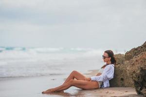 jong gelukkig vrouw Aan de strand genieten haar zomer vakantie. meisje is gelukkig en kalmte in haar blijven Aan de strand foto