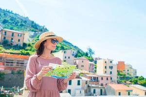 jong vrouw met kaart Bij oud dorp riomaggiore, cinque terrein, ligurië, Italië. Europese Italiaans vakantie. foto