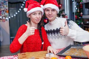 gelukkig familie in de kerstman hoeden bakken Kerstmis peperkoek koekjes samen foto