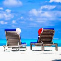Kerstmis concept strand ligstoelen met rood de kerstman en rietje hoeden achtergrond mooi turkoois zee foto