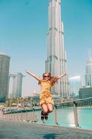 gelukkig meisje wandelen in Dubai met wolkenkrabber in de achtergrond. foto