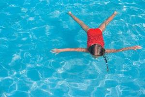 weinig aanbiddelijk meisje zwemmen in de zwembad foto