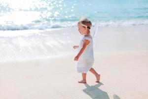 schattig klein meisje veel plezier op tropisch strand tijdens vakantie foto