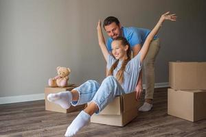 gelukkig vader met dochter hebben pret in hun nieuw huis. familie genieten hun in beweging dag foto