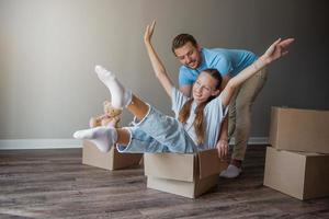 gelukkig vader met dochter hebben pret in hun nieuw huis. familie genieten hun in beweging dag foto