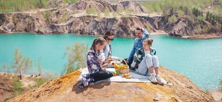 panorama van jong familie Aan picknick na wandelen in bergen. mooi visie van blauw meer foto