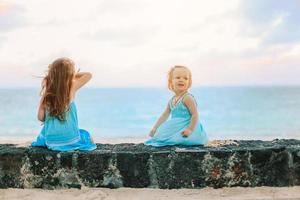 weinig gelukkig grappig meisjes hebben een veel van pret Bij tropisch strand spelen samen. foto