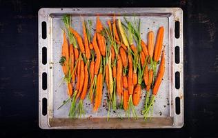 rauw biologisch wortels met tijm, honing en citroen bereid voor roosteren Aan een bakken vel. biologisch veganistisch voedsel. visie van bovenstaand foto