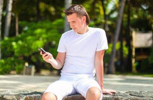 jong Mens pratend Aan telefoon gedurende tropisch strand vakantie