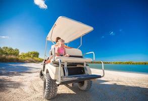 weinig meisje met vader golf kar Aan tropisch strand foto