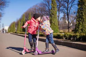 weinig gelukkig meisjes met scooter buitenshuis foto