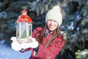 jong gelukkig vrouw met rood Kerstmis lantaarn in de sneeuw foto