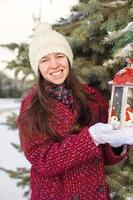 jong mooi gelukkig vrouw met rood Kerstmis lantaarn in de sneeuw foto