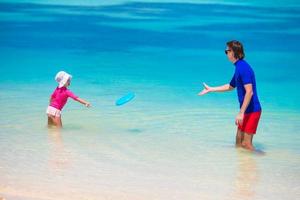 gelukkig weinig meisje met jong vader hebben pret Aan tropisch strand foto