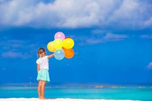 schattig klein meisje speelt met ballonnen op het strand foto