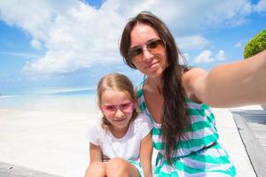moeder en weinig meisje nemen selfie achtergrond de zee foto