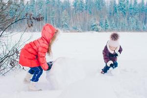 aanbiddelijk weinig gelukkig meisjes rodelen in winter besneeuwd dag. foto