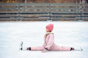 weinig aanbiddelijk meisje zittend Aan ijs met skates na vallen foto