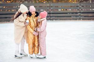 weinig aanbiddelijk meisjes met haar moeder het schaatsen Aan ijsbaan foto