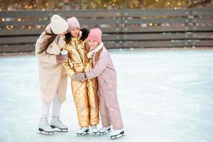 weinig aanbiddelijk meisjes met haar moeder het schaatsen Aan ijsbaan foto