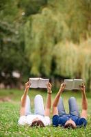 ontspannen jong paar lezing boeken terwijl aan het liegen Aan gras foto