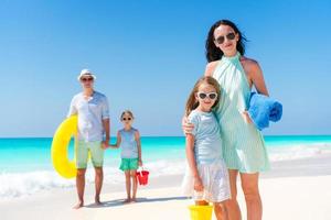 gelukkig mooi familie van vier Aan een tropisch strand vakantie foto