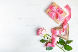 geschenk, houten hart, roze roos, polka dots lint Aan houten wit achtergrond. top visie, kopiëren ruimte. foto