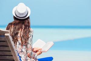 portret van een jong vrouw ontspannende Aan de strand, lezing een boek foto