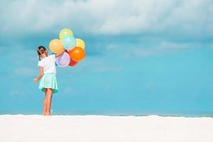 schattig klein meisje speelt met ballonnen op het strand foto