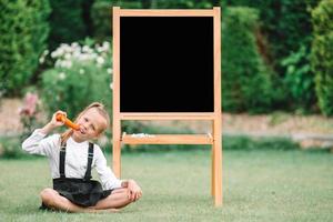 gelukkig weinig schoolmeisje met een schoolbord buitenshuis foto
