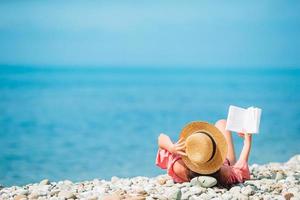 jong vrouw lezing boek gedurende tropisch wit strand foto