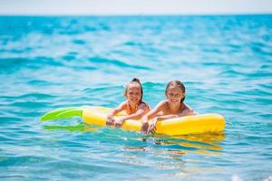 weinig meisjes hebben pret Bij tropisch strand gedurende zomer vakantie spelen samen foto