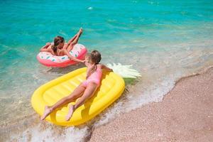 weinig meisjes hebben pret Bij tropisch strand gedurende zomer vakantie spelen samen foto