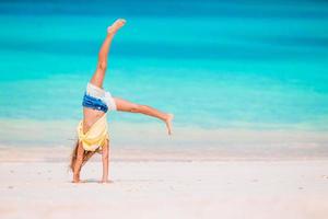 actief weinig meisje Bij strand hebben een veel van plezier. schattig kind maken sportief opdrachten Aan de kust foto