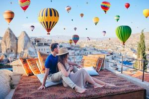 gelukkig jong paar gedurende zonsopkomst aan het kijken heet lucht ballonnen in Cappadocië, kalkoen foto