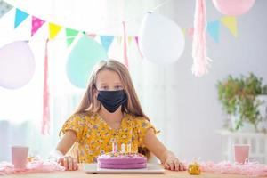 Kaukasisch meisje is dromerig glimlachen en op zoek Bij verjaardag regenboog taart. feestelijk kleurrijk achtergrond met ballonnen. verjaardag partij en wensen concept. foto