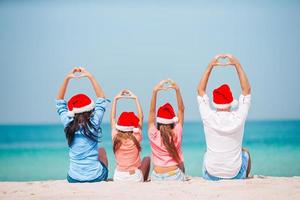 gelukkig familie met twee kinderen in de kerstman hoed Aan zomer vakantie foto