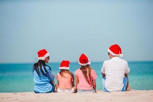 gelukkig familie met twee kinderen in de kerstman hoed Aan zomer vakantie foto