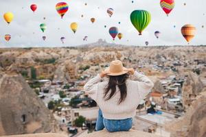 gelukkig jong vrouw gedurende zonsopkomst aan het kijken heet lucht ballonnen in Cappadocië, kalkoen foto