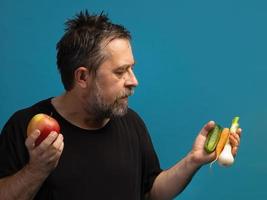 Mens in een zwart t-shirt houdt fruit en groenten foto