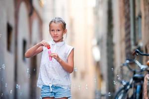 aanbiddelijk weinig meisje buitenshuis blazen zeep bubbels in Europese stad. portret van Kaukasisch kind genieten zomer vakantie in Italië foto