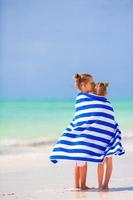 weinig meisjes verpakt in handdoek na zwemmen Bij tropisch strand foto