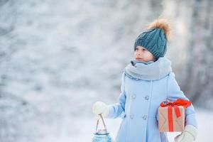 aanbiddelijk meisje met Kerstmis doos geschenk in winter buitenshuis foto