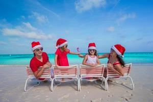 gelukkig familie in Kerstmis hoeden hebben pret Aan wit strand foto