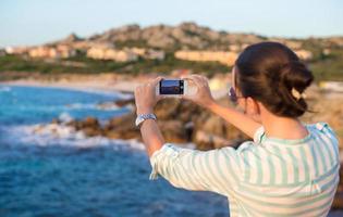 jong vrouw nemen een afbeelding Aan telefoon gedurende strand vakantie foto